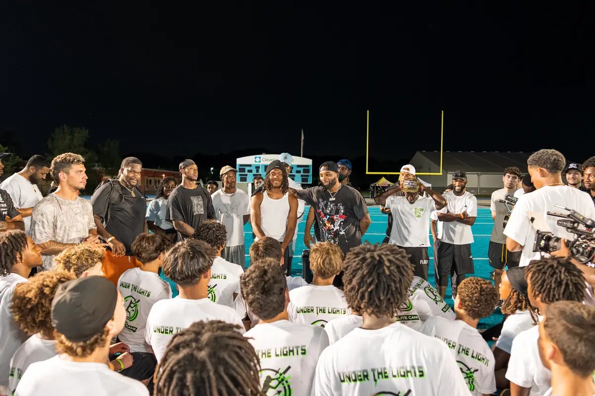 Young athletes gathered around mentors at an evening youth football event